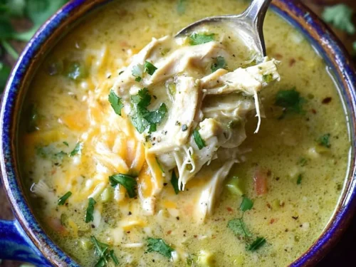 Bowl of flavorful Green Enchilada Chicken Soup garnished with cilantro and tortilla strips.