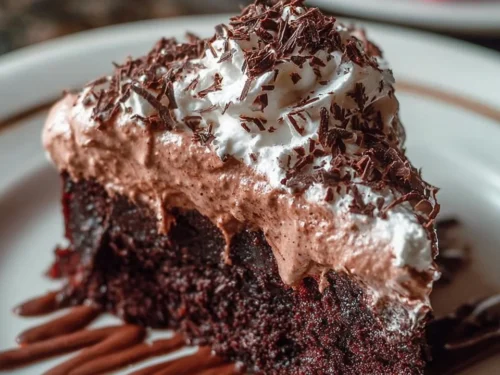 A slice of Chocolate Three Milks Cake topped with whipped cream and chocolate shavings.