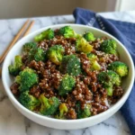 Plate of ground beef and broccoli stir-fry with rice on a wooden table