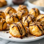 Golden toasted vegan coconut macaroons drizzled with melted dark chocolate on a ceramic plate.
